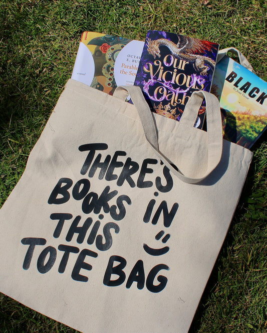 Tote bag with 'There's books in this tote bag' text on grass