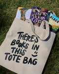 Tote bag with 'There's books in this tote bag' text on grass